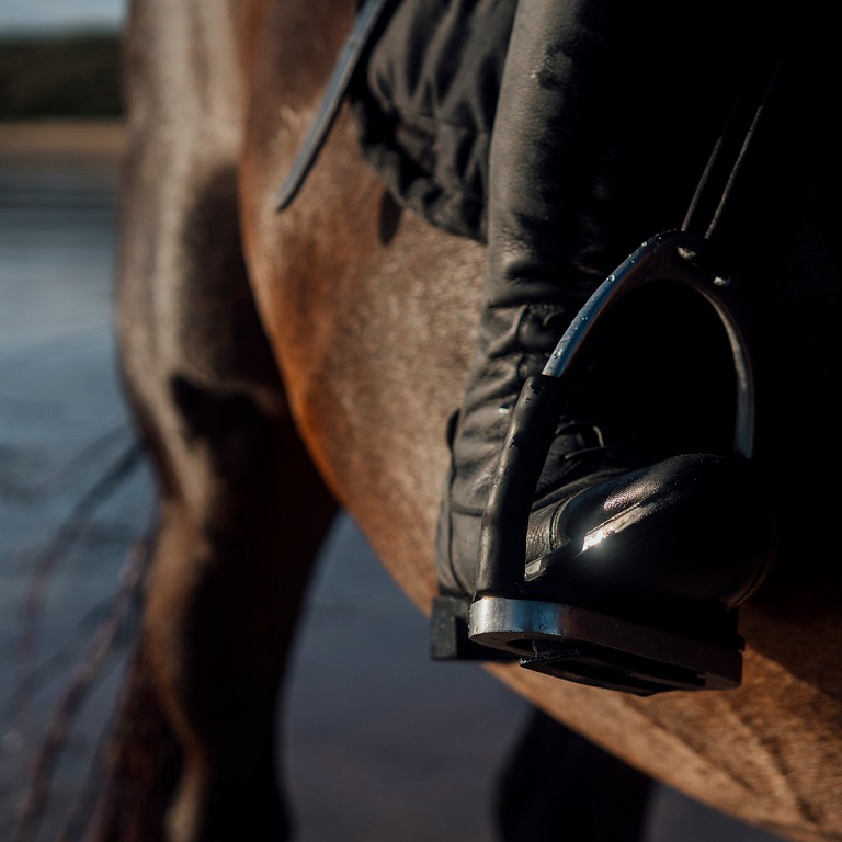 Close up of rider's boot in stirrup on a horse